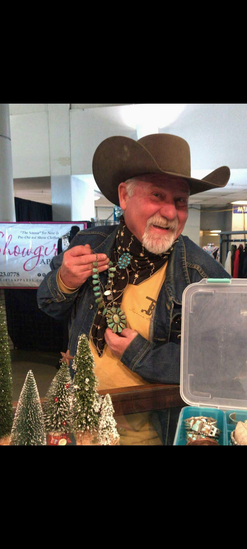 Man in cowboy hat holding a necklace with Christmas trees in the background | Texanna Belles Jewelry