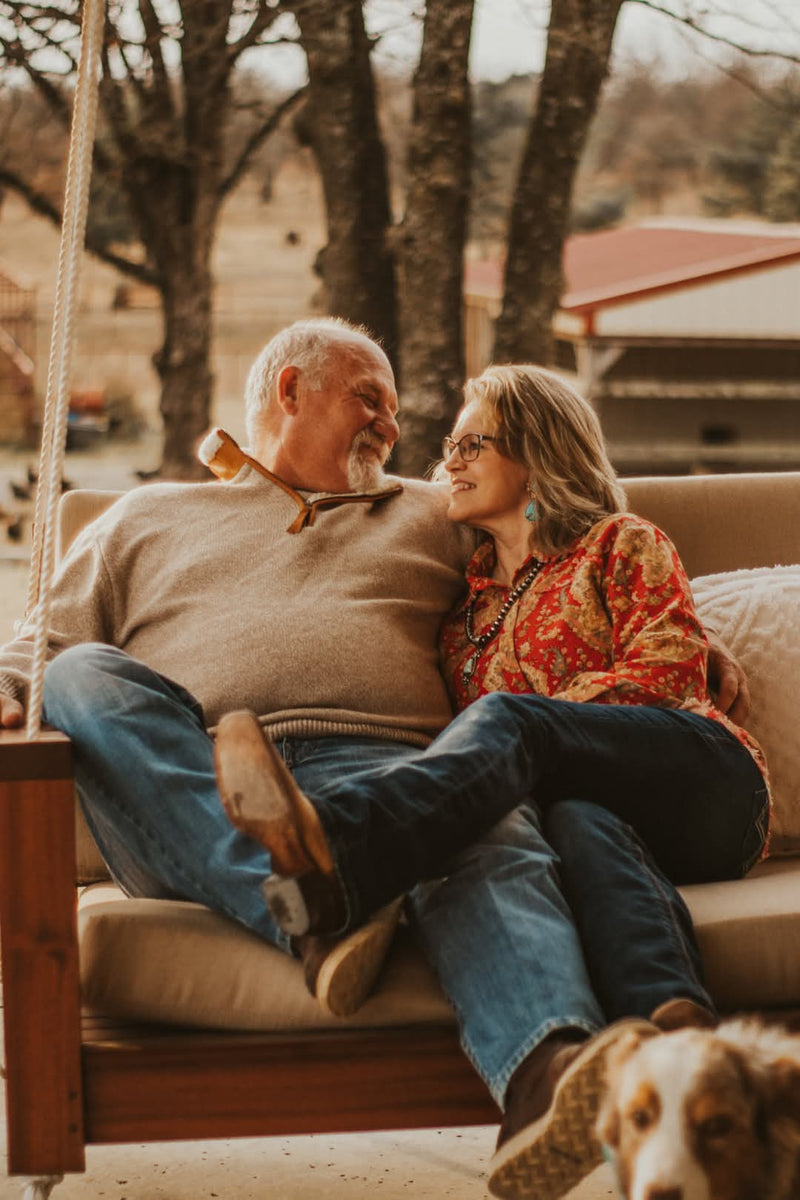 Senior couple sitting on a swing with a dog in the foreground | Texanna Belles Jewelry