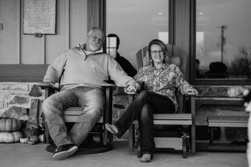 Two people sitting on chairs in a casual setting with a window in the background | Texanna Belles Jewelry