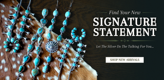A promotional banner showing multiple turquoise and silver jewelry pieces arranged on a spotted animal hide over a dark wood surface, with large text reading 'Find Your New Signature Statement' and a 'Shop New Arrivals' button on the right.
