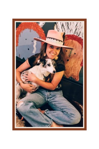 Person wearing a cowboy hat and holding a dog, sitting on a horse with a colorful background  | Texanna Belles Jewelry